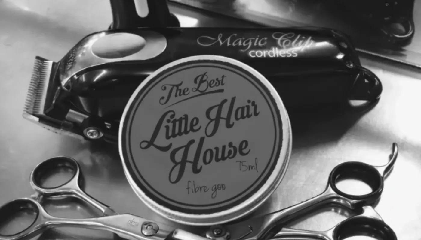 The shop's own fibre goo tin, a Magic Clip cordless clipper and scissors laid out on the barber's station